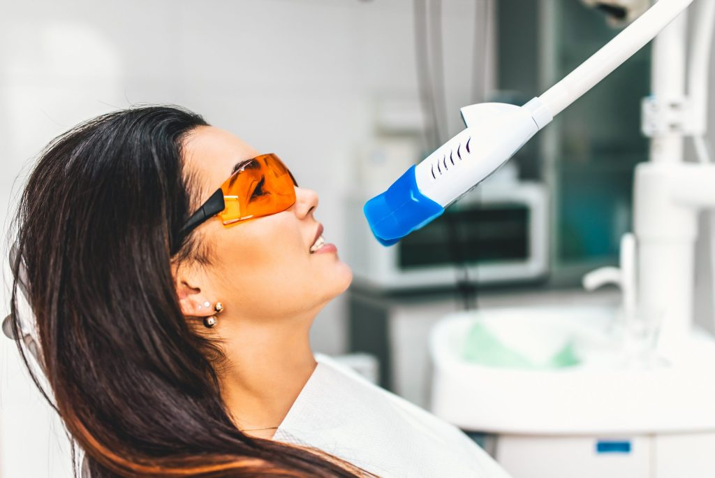 Teeth whitening in dental clinic for pretty female patient